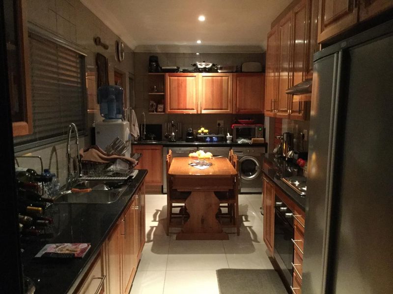 A functional galley-style kitchen featuring warm wooden cabinetry, dark granite countertops, and integrated appliances, offering a practical layout for daily cooking and dining.