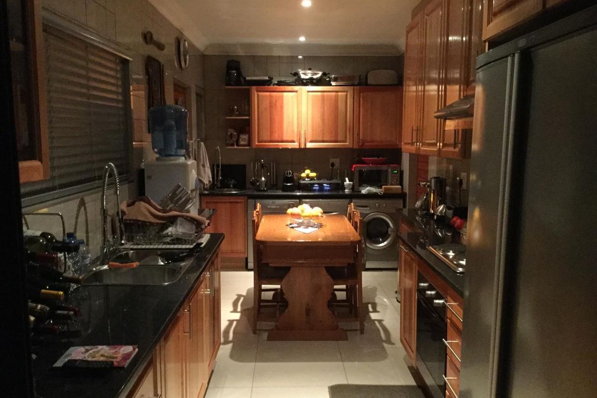 A functional galley-style kitchen featuring warm wooden cabinetry, dark granite countertops, and integrated appliances, offering a practical layout for daily cooking and dining.