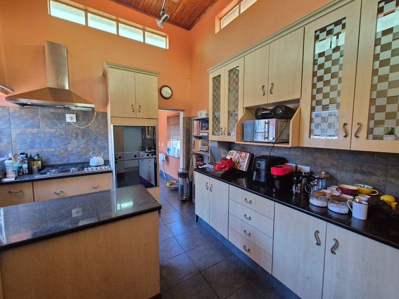 Spacious kitchen featuring light wood cabinetry, granite countertops, built-in oven, gas hob, and high timber ceilings with clerestory windows for natural light.