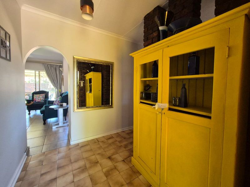 A bright hallway featuring ceramic floor tiles, an arched entryway leading to the living area, and a decorative exposed brick column.
