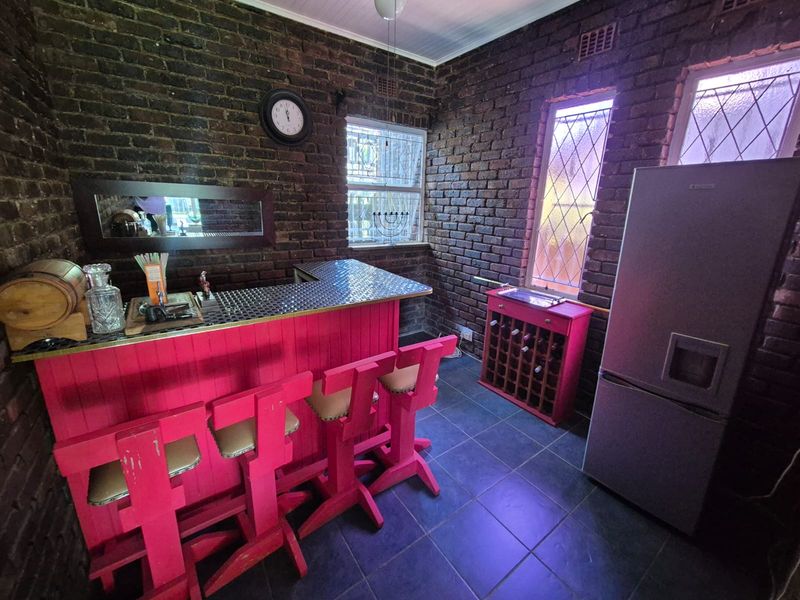 A dedicated bar area featuring exposed brick walls, tiled flooring, and a built-in bar counter with leaded glass windows.