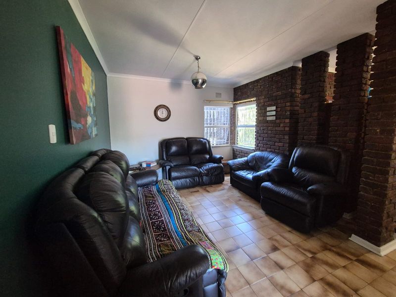 A living room featuring an exposed brick wall, ceramic tile flooring, and security bars on the windows, offering a solid foundation for modern updates.