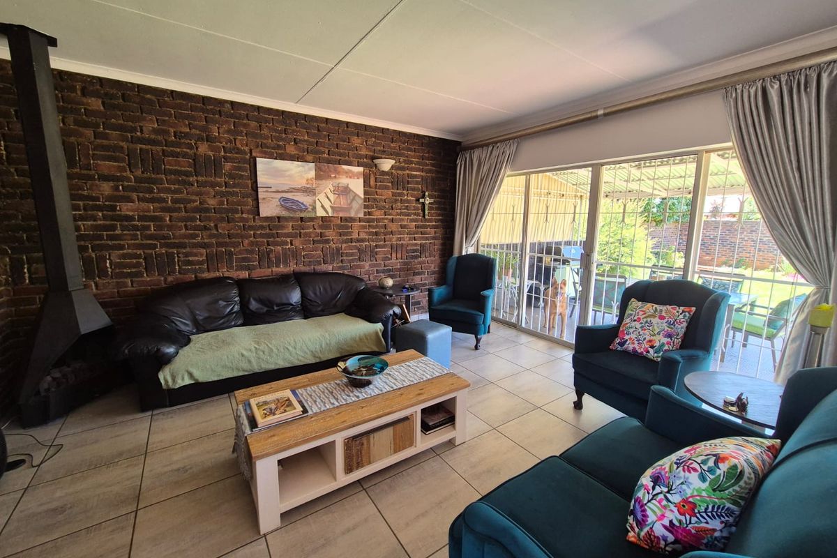 A comfortable living room featuring an exposed brick wall, a freestanding fireplace, and large sliding glass doors that provide access to the outdoor area.