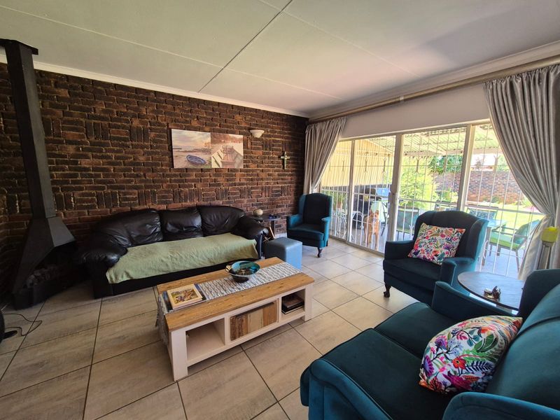 A comfortable living room featuring an exposed brick wall, a freestanding fireplace, and large sliding glass doors that provide access to the outdoor area.