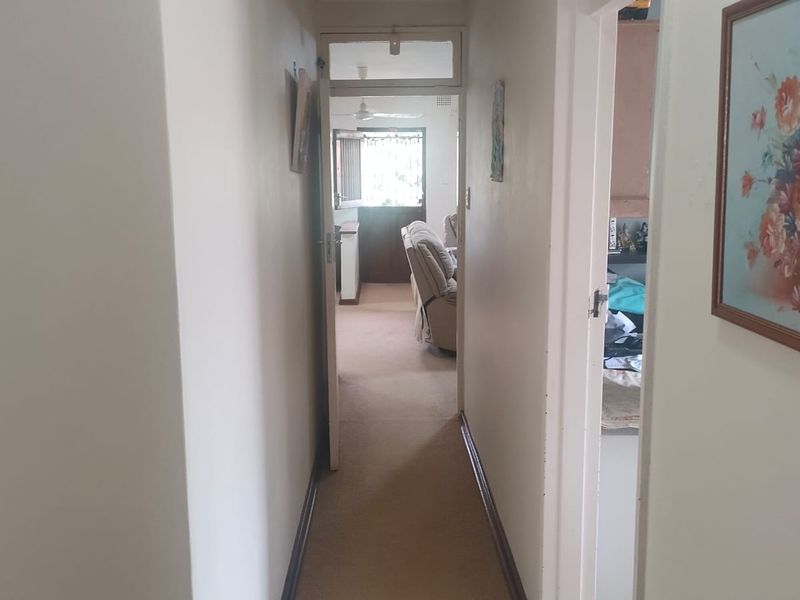 A functional interior hallway connecting living spaces, featuring neutral wall finishes and carpeted flooring.