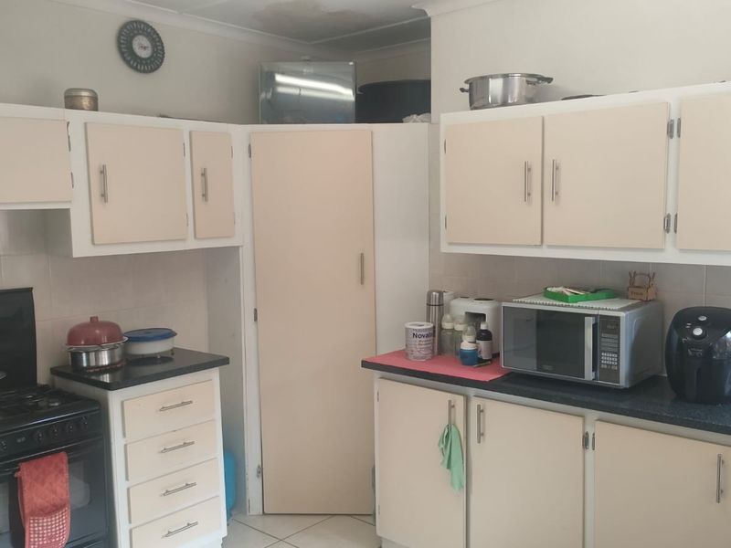 A functional kitchen featuring dated cabinetry, laminate countertops, and a built-in oven, with visible ceiling water staining requiring attention.