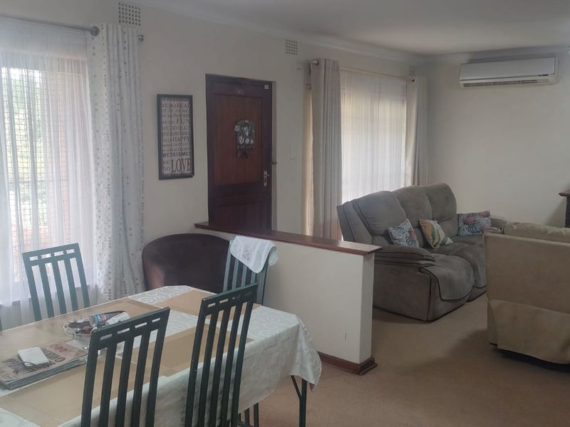 Open-plan living and dining area featuring a fireplace, split-system air conditioning, and large windows providing natural light.