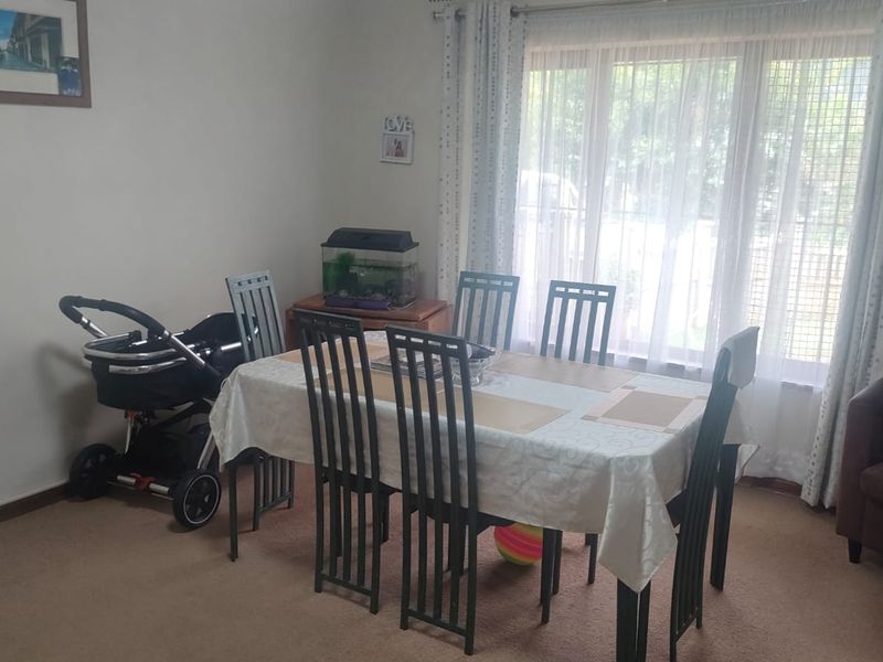 A dining room featuring carpeted flooring and large windows with installed curtain tracks, providing a functional space for family meals.