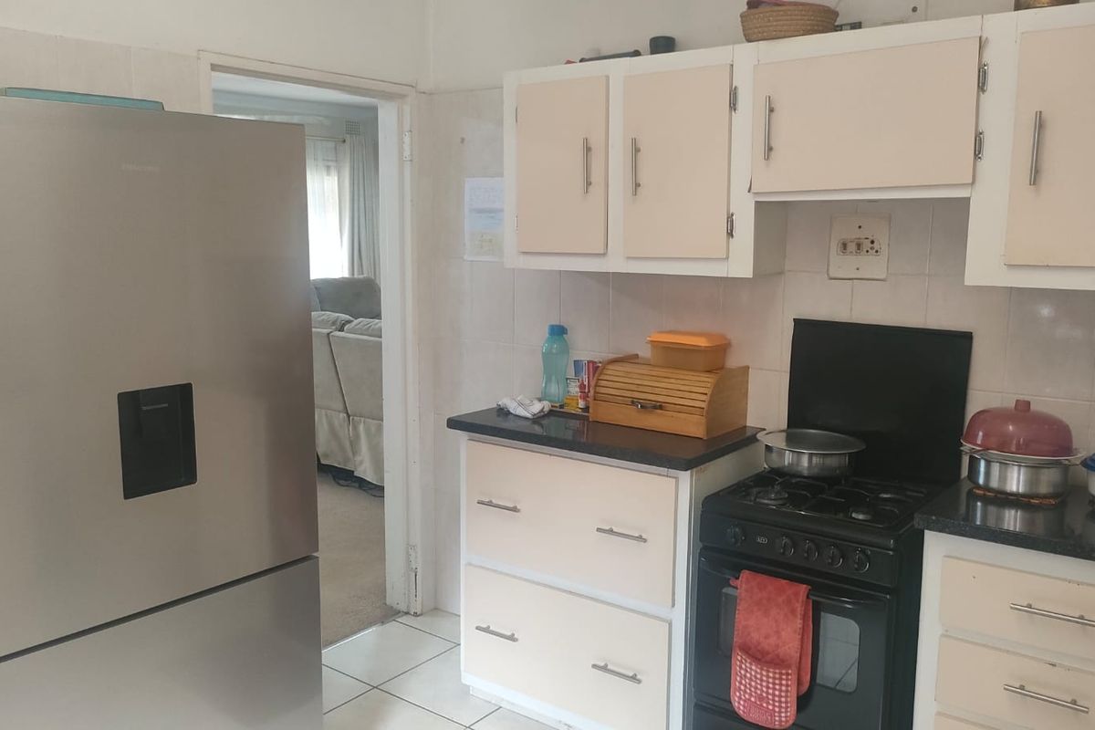 A functional kitchen featuring built-in cabinetry, a gas stove with oven, and tiled backsplash, offering a practical layout for daily meal preparation.