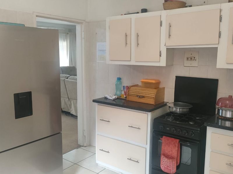 A functional kitchen featuring built-in cabinetry, a gas stove with oven, and tiled backsplash, offering a practical layout for daily meal preparation.