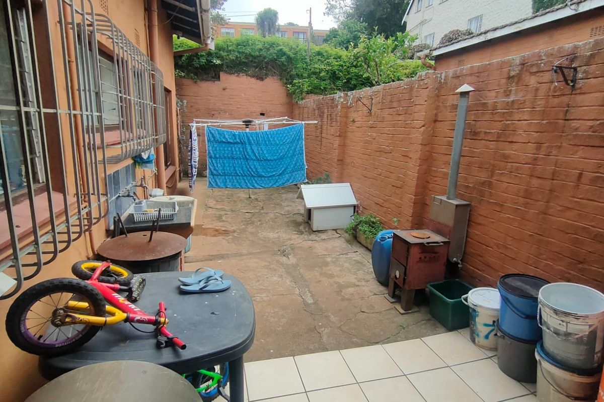 A private rear courtyard area featuring brick boundary walls and concrete paving, offering a functional outdoor space for the townhouse.