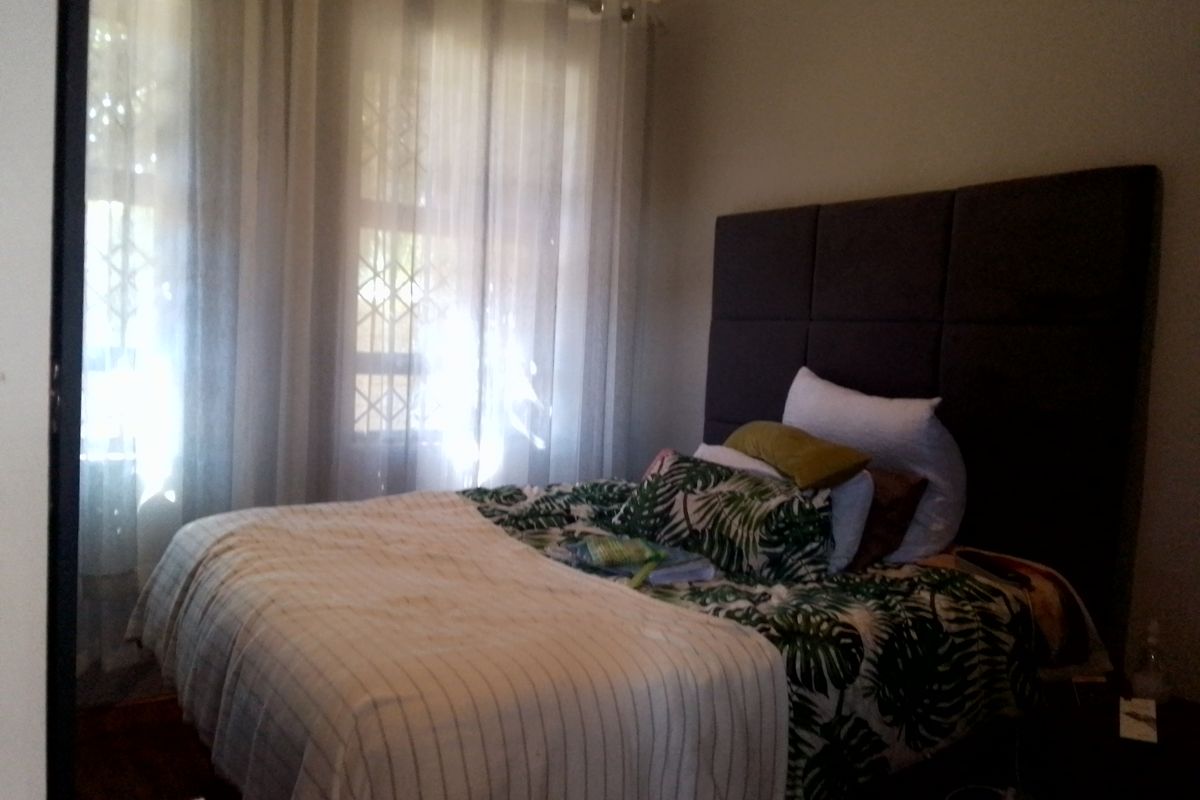 A bedroom featuring a large upholstered headboard, decorative cornice, and windows fitted with security gates.
