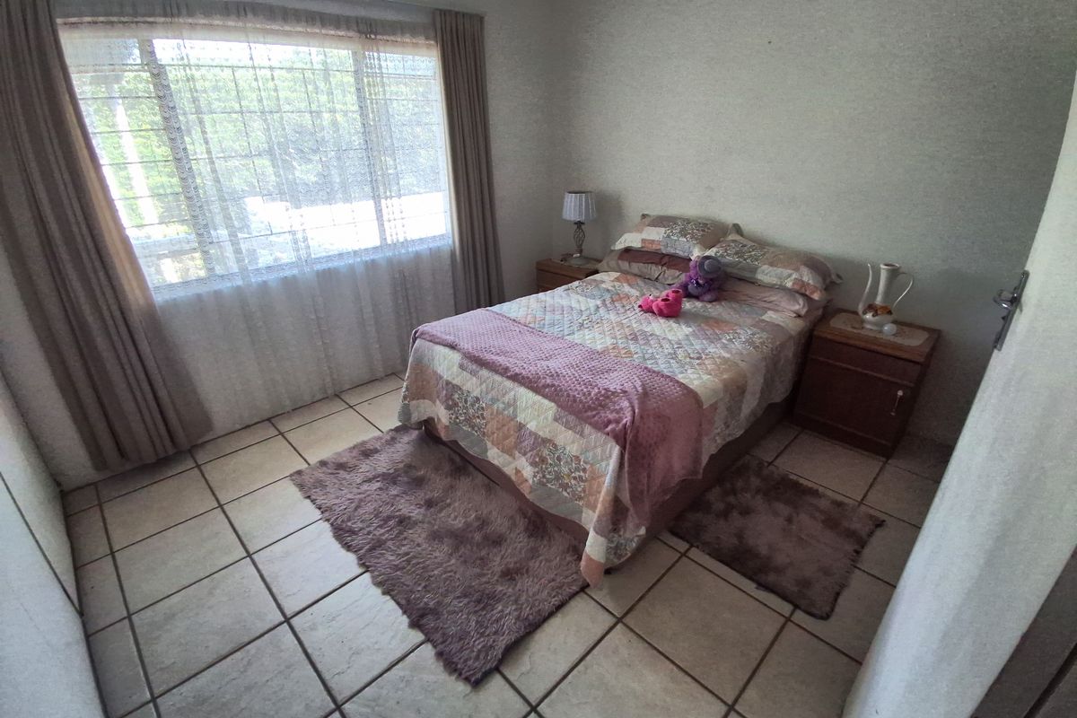 A bedroom featuring tiled flooring and a large window with curtains, providing natural light.