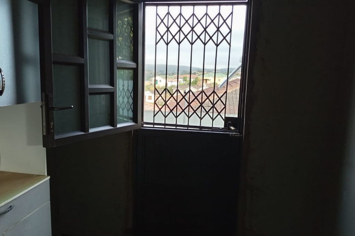 A view from an interior doorway featuring a security gate and a glimpse of the surrounding neighborhood.