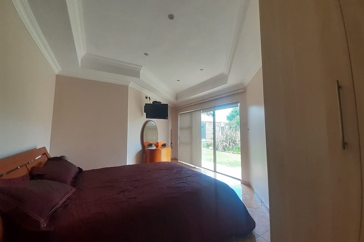 Spacious bedroom featuring a recessed ceiling, tiled flooring, and a sliding glass door providing direct access to the garden.