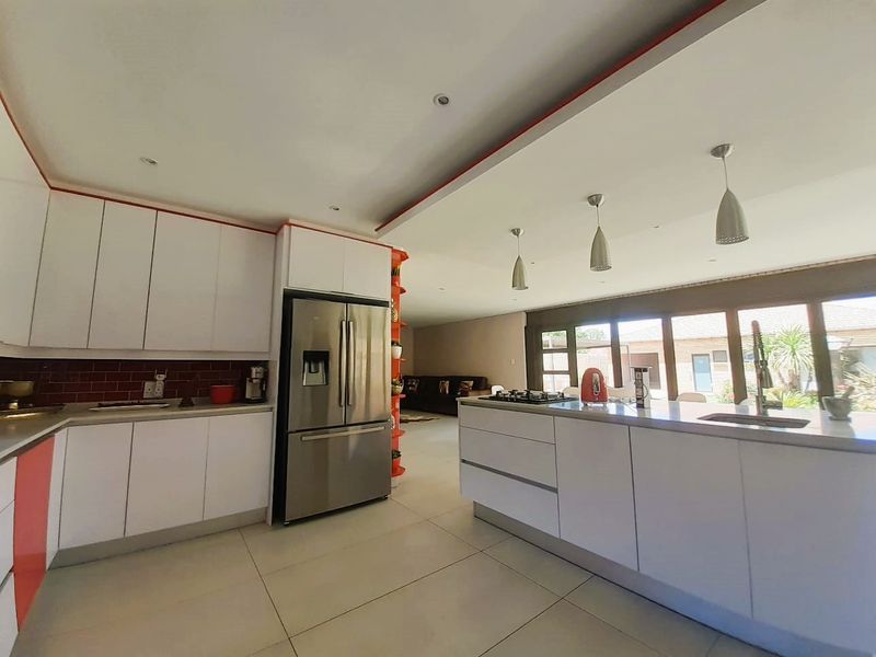 Modern open-plan kitchen featuring a central island, sleek white cabinetry, gas hob, and large sliding doors providing seamless access to the outdoor area.