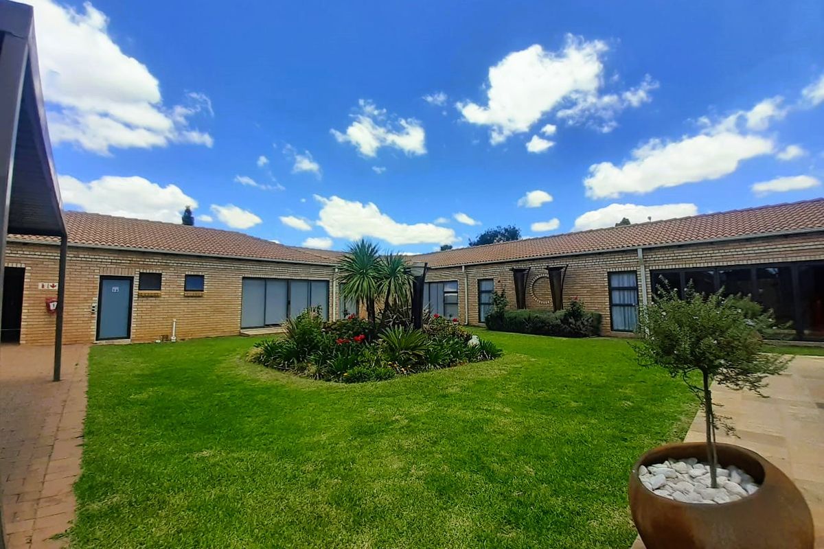 A well-maintained rear courtyard featuring a central landscaped garden, brick exterior walls, and multiple access points via sliding glass doors.