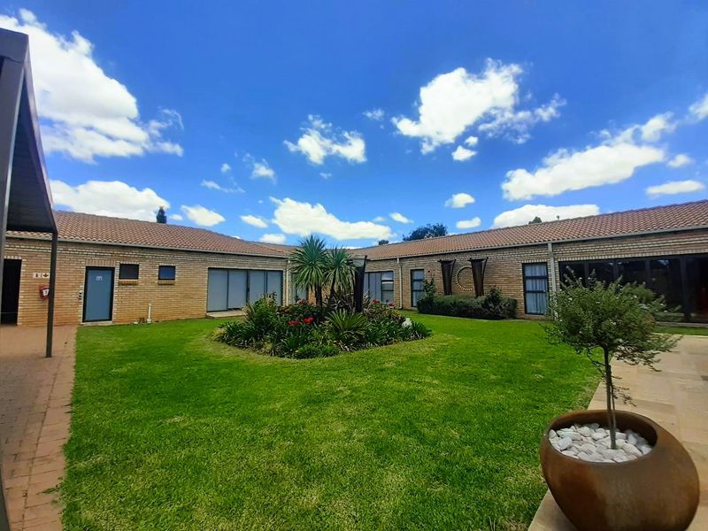 A well-maintained rear courtyard featuring a central landscaped garden, brick exterior walls, and multiple access points via sliding glass doors.