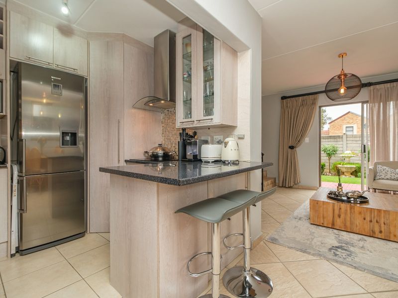 Open-plan kitchen and living area featuring light wood cabinetry, granite countertops, and direct access to a private garden through sliding glass doors.