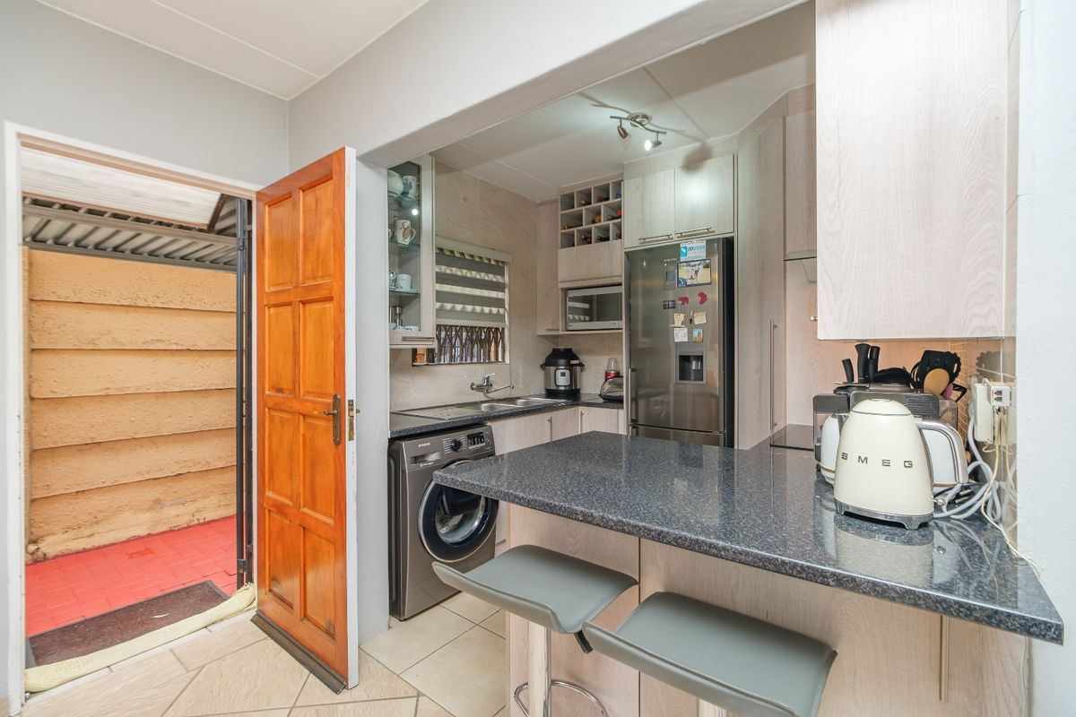 Compact kitchen featuring light wood cabinetry, granite countertops, a breakfast bar, and direct access to an outdoor utility area.