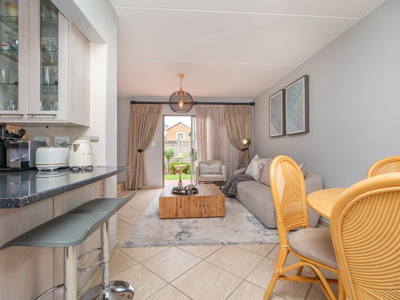 Open-plan living and kitchen area featuring tiled floors, granite countertops, and direct access to the rear patio through a sliding glass door.