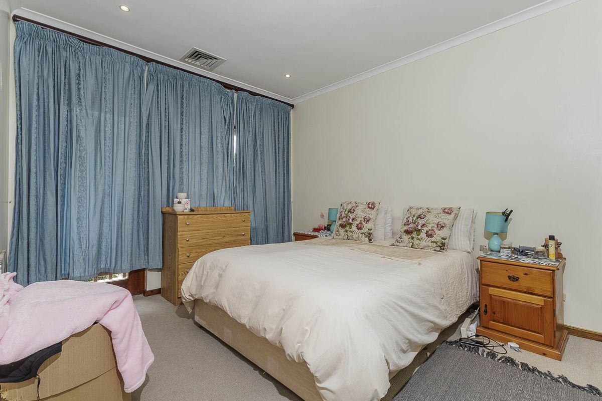 A functional bedroom featuring neutral carpeted flooring, recessed downlighting, and integrated ducted air conditioning, providing a comfortable and well-lit living space.