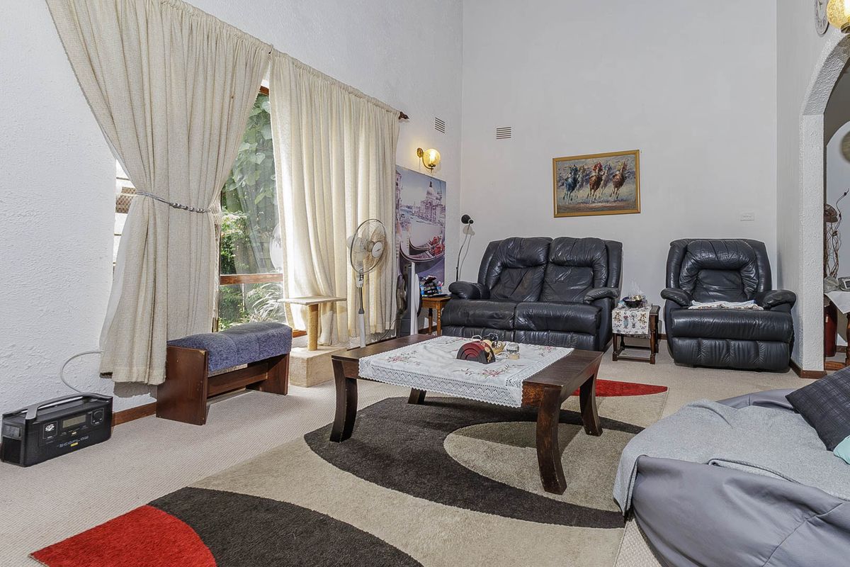 Spacious living room featuring a high vaulted ceiling, large window with natural light, and an arched entryway leading to adjacent areas.