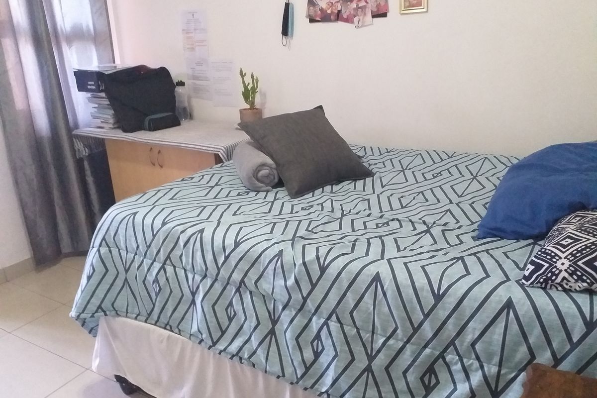 A bedroom featuring tiled flooring and a built-in desk area, providing a functional space for rest and study.
