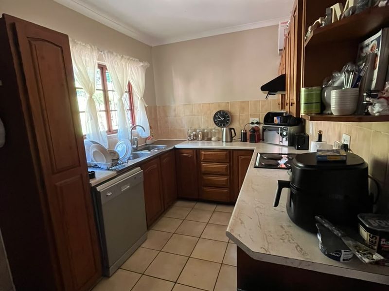 A functional kitchen featuring traditional wooden cabinetry, laminate countertops, ceramic tile backsplash, and tiled flooring, offering a classic layout with ample storage space.