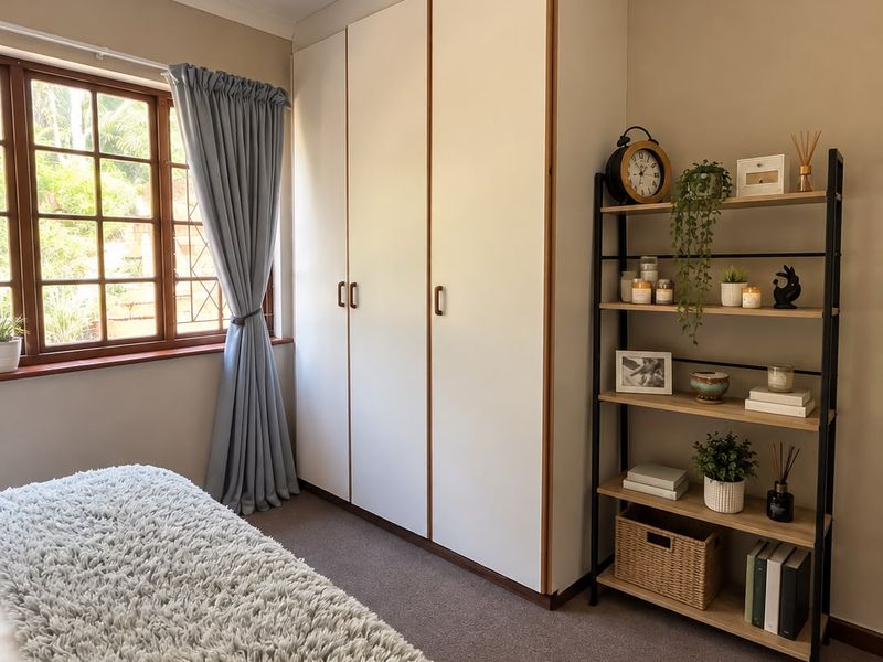 A well-maintained bedroom featuring built-in wardrobes, carpeted flooring, and a timber-framed window providing natural light.