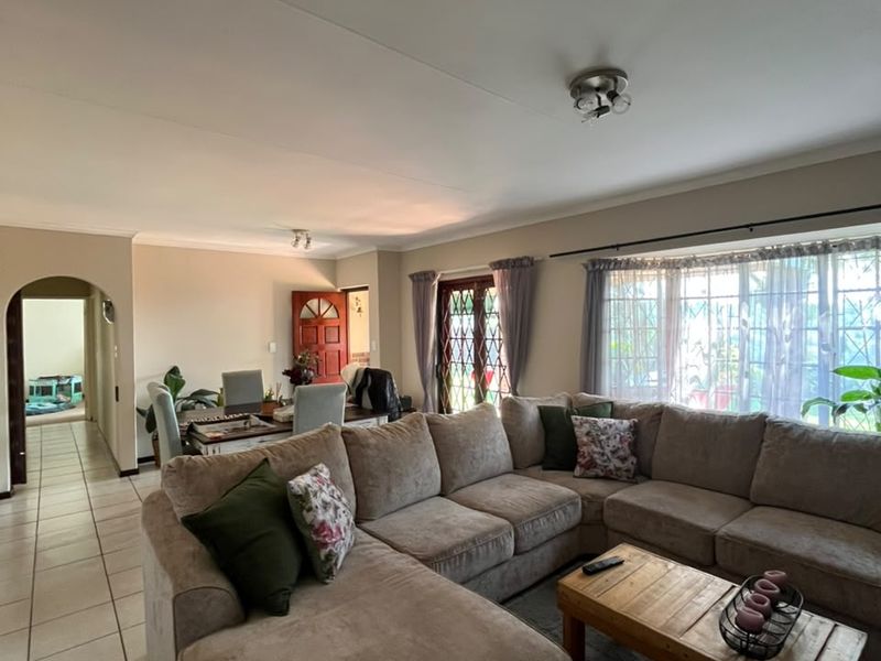 Open plan living area featuring tiled flooring, a bay window, and an arched entryway leading to the rest of the home.