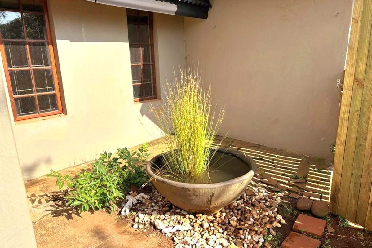 A private rear courtyard area featuring stone paving, timber-framed windows, and a decorative water feature against the cottage exterior.