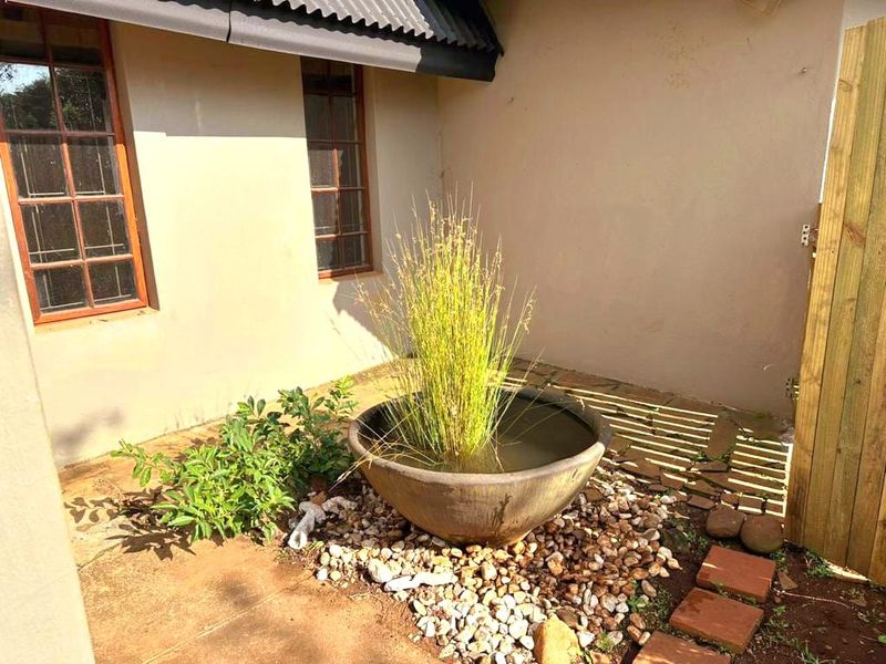 A private rear courtyard area featuring stone paving, timber-framed windows, and a decorative water feature against the cottage exterior.