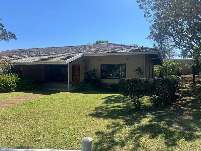 Front view of a townhouse featuring a tiled roof, covered entrance, and a well-maintained front lawn with established garden beds.
