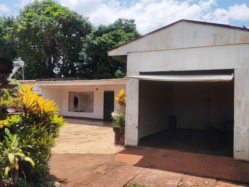 Exterior view of a detached garage structure with a concrete driveway and security features on the adjacent building entrance.