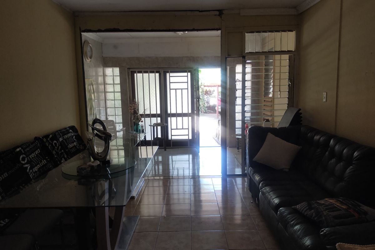 Living room featuring tiled flooring, crown molding, and a security gate leading to an outdoor area. The space requires cosmetic updates to improve condition.