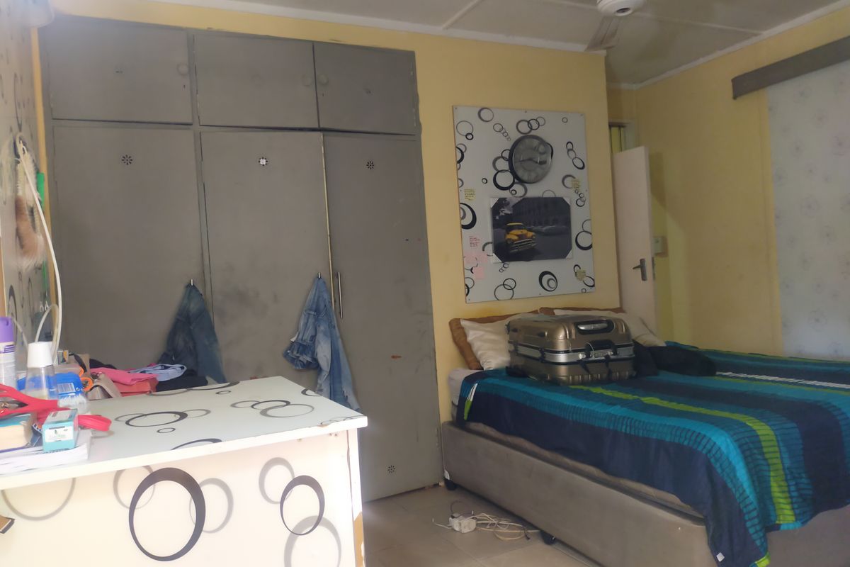 A bedroom featuring built-in cupboards and a ceiling fan, requiring cosmetic updates to improve the overall aesthetic and condition of the space.