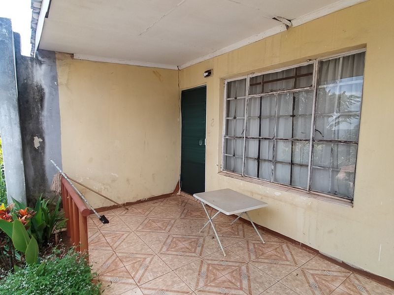 A covered patio area featuring tiled flooring and steel-framed windows, requiring maintenance and cosmetic updates to improve its overall condition and appeal.