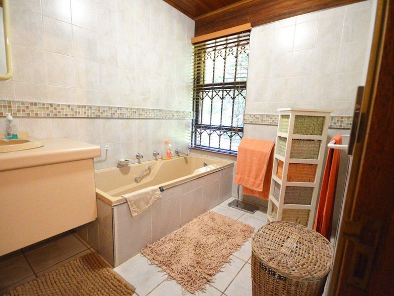 A functional bathroom featuring a built-in vanity, bathtub, and tiled finishes, offering a classic layout with natural light from the window.