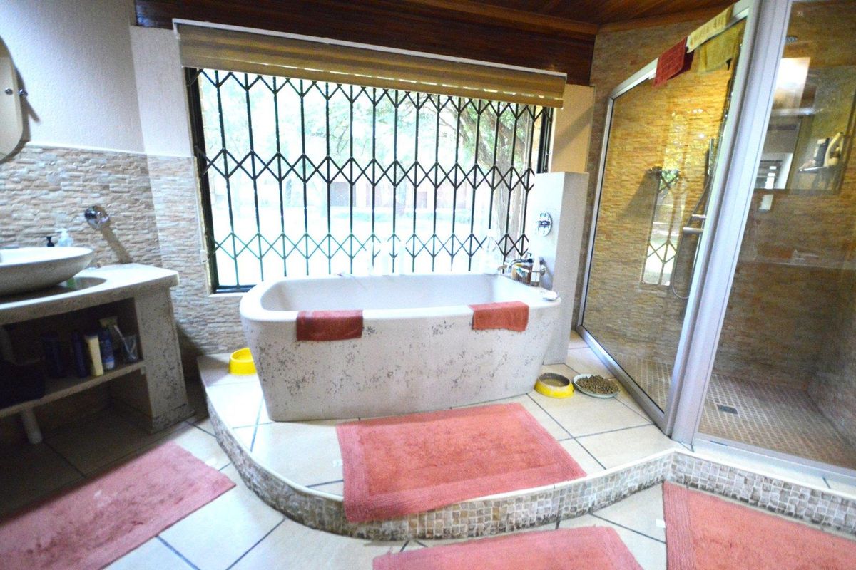 A bathroom featuring a raised platform with a freestanding bathtub, a separate glass-enclosed shower, and a vessel sink with stone-clad wall finishes.