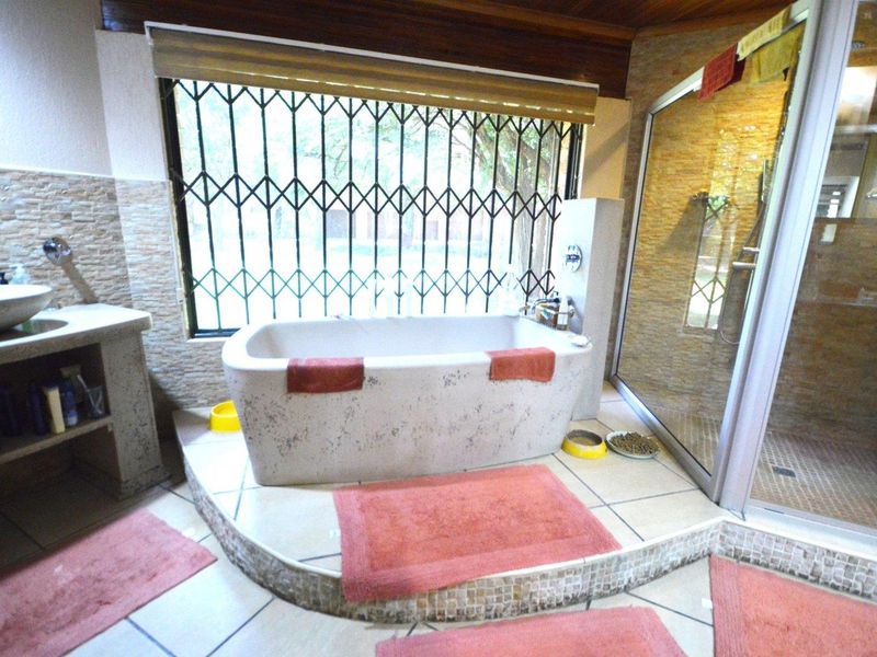 A bathroom featuring a raised platform with a freestanding bathtub, a separate glass-enclosed shower, and a vessel sink with stone-clad wall finishes.