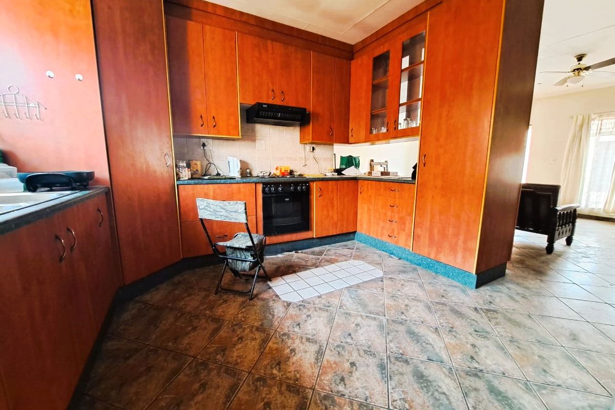 A functional kitchen featuring wood-look cabinetry, built-in oven, extractor fan, and tiled flooring, offering a classic layout with potential for modern updates.