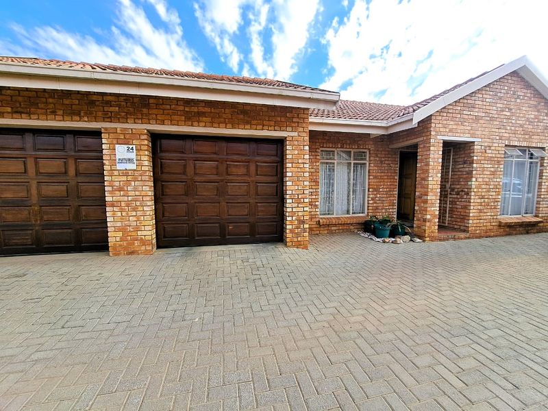 Front exterior view of a townhouse featuring a double garage, face-brick facade, and a paved driveway.
