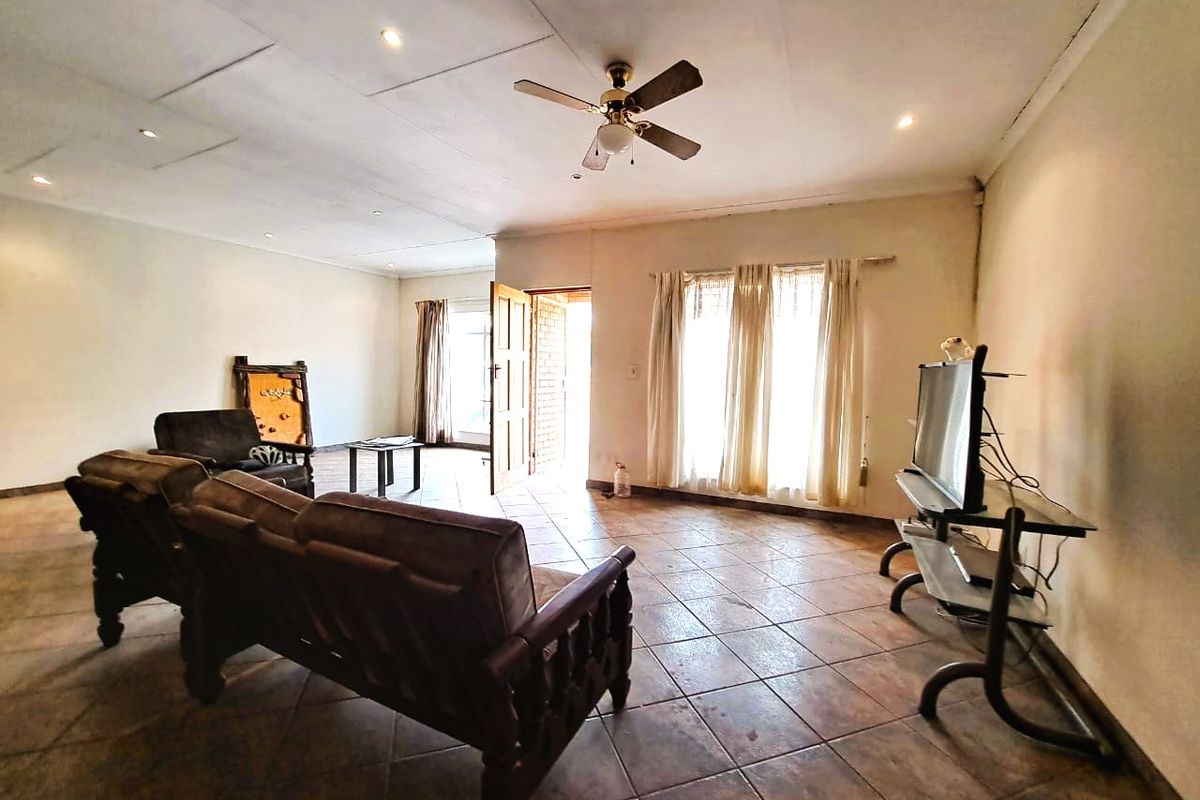 Spacious living room featuring tiled flooring, a ceiling fan, and direct access to the exterior through a timber door.