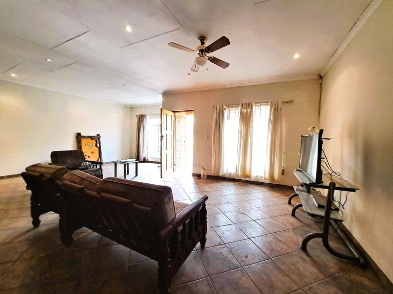 Spacious living room featuring tiled flooring, a ceiling fan, and direct access to the exterior through a timber door.