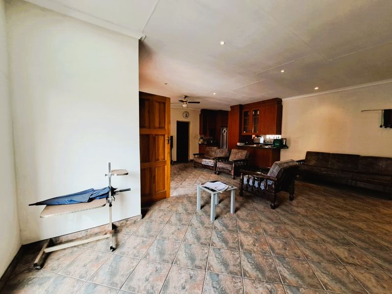 Open-plan living area featuring tiled flooring, recessed lighting, and wooden cabinetry, offering a functional layout with potential for modernization.