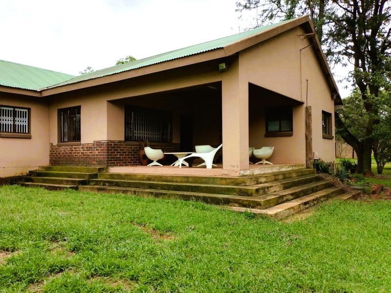 A covered outdoor patio area featuring concrete steps and brick detailing, providing a functional space for outdoor relaxation overlooking the garden.