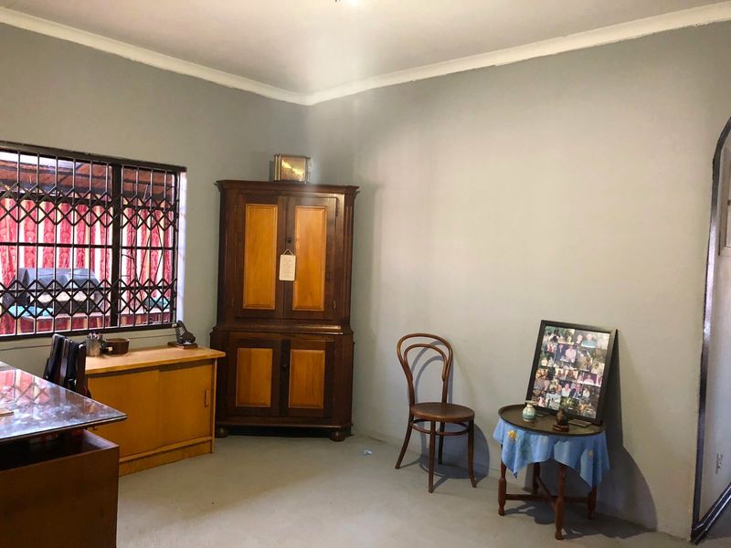 A living room area featuring a window with a fixed security gate and simple wall finishes.