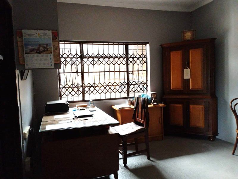 A functional home office space featuring a window with a fitted security gate and neutral wall finishes.