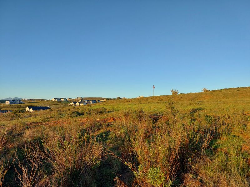 A scenic view of the surrounding landscape and nearby residential properties, showcasing the natural terrain and open space of the area.